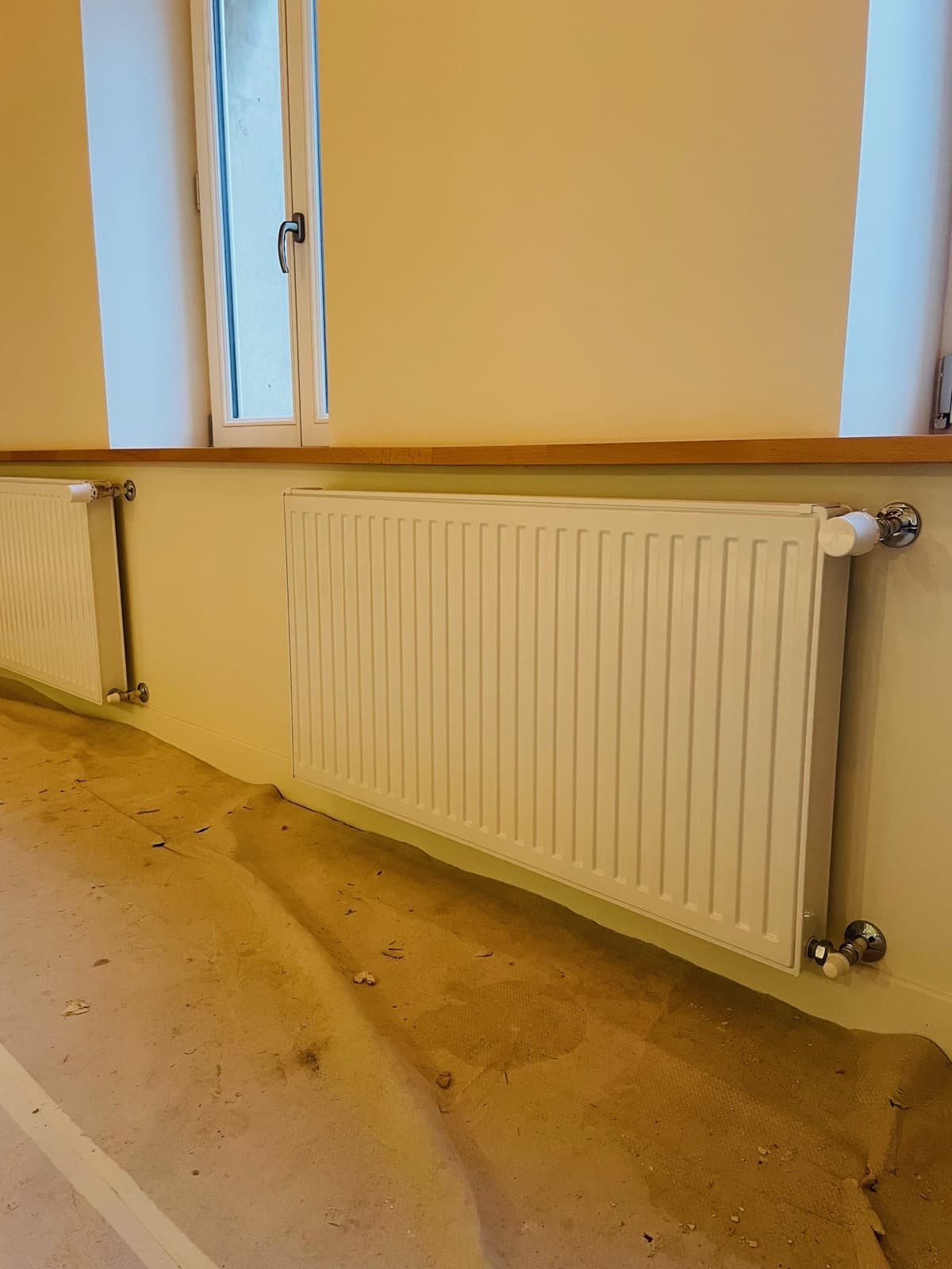 Radiateur installé près d’une fenêtre, sol protégé pendant travaux