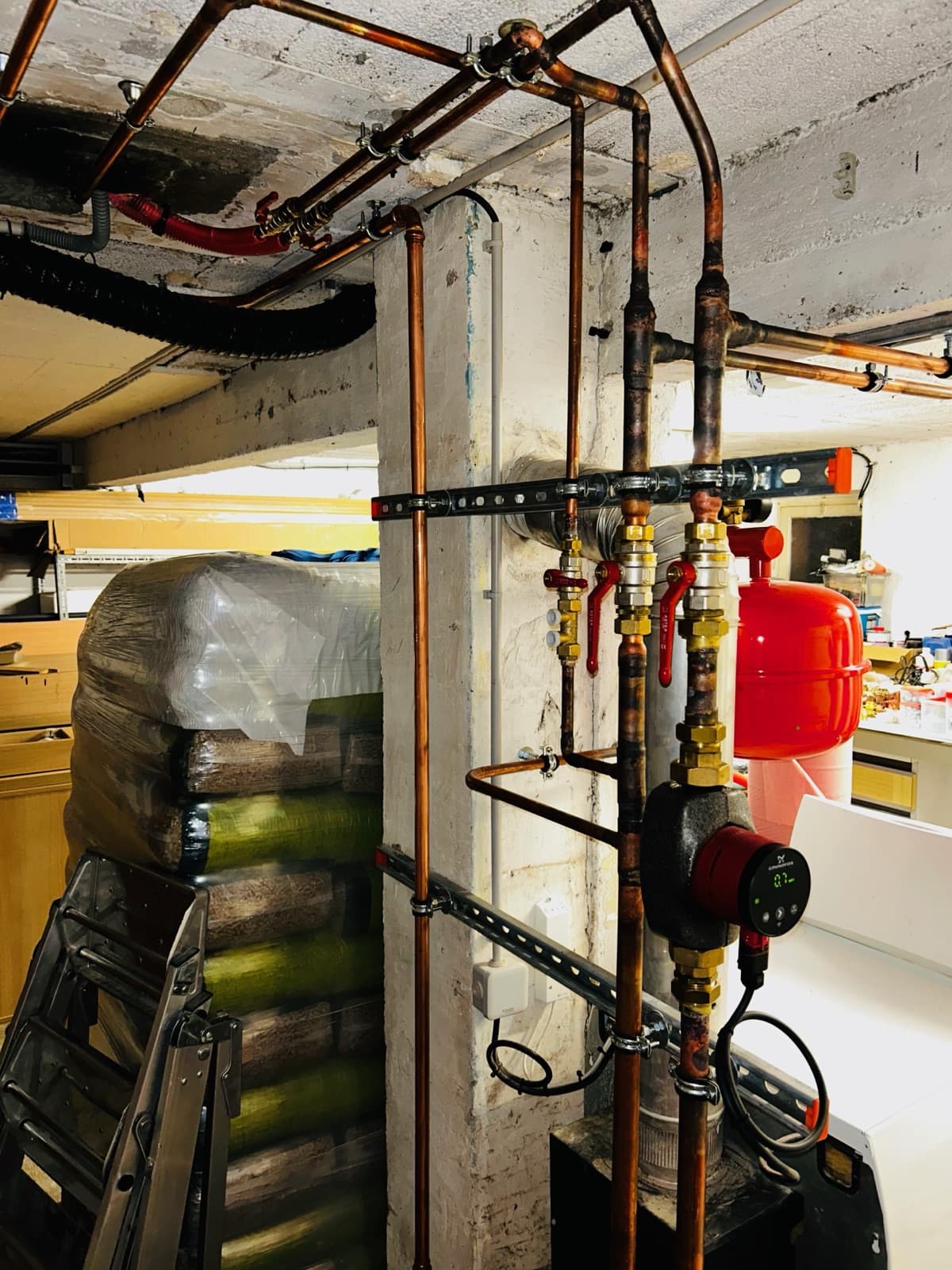 Distribution en cuivre au plafond d’un sous-sol technique, chaudière à granulés bois