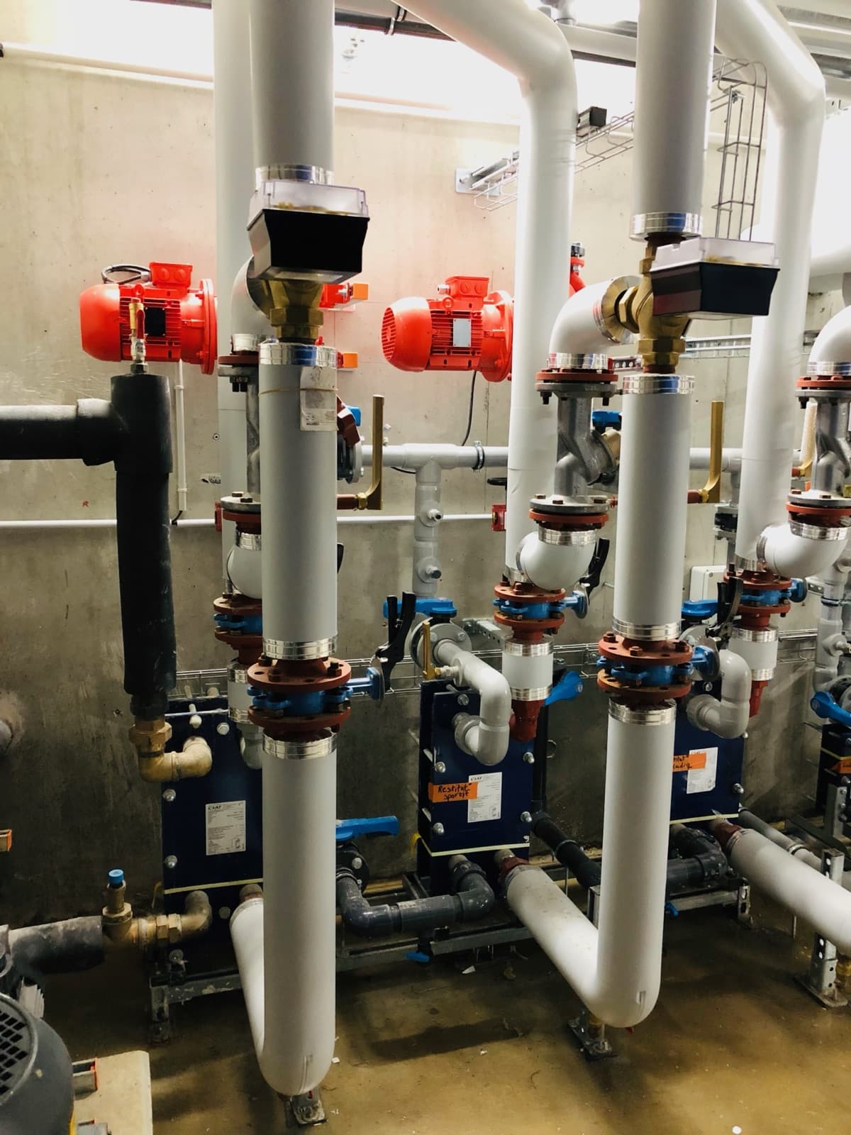 Salle des machines d’une chaufferie collective, échangeurs et pompes de circulation