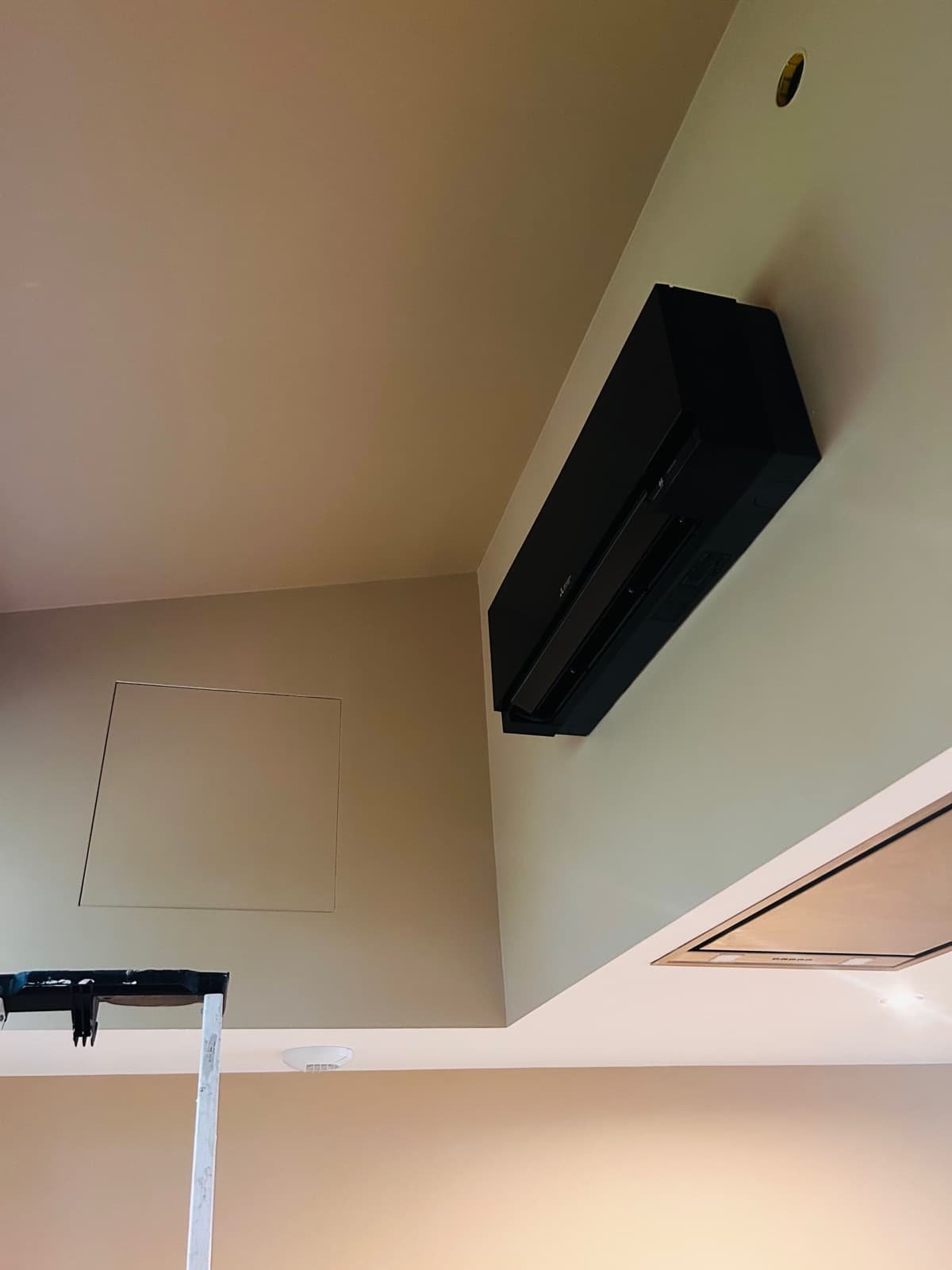 Unité intérieure design noire installée en hauteur dans l’angle d’une pièce