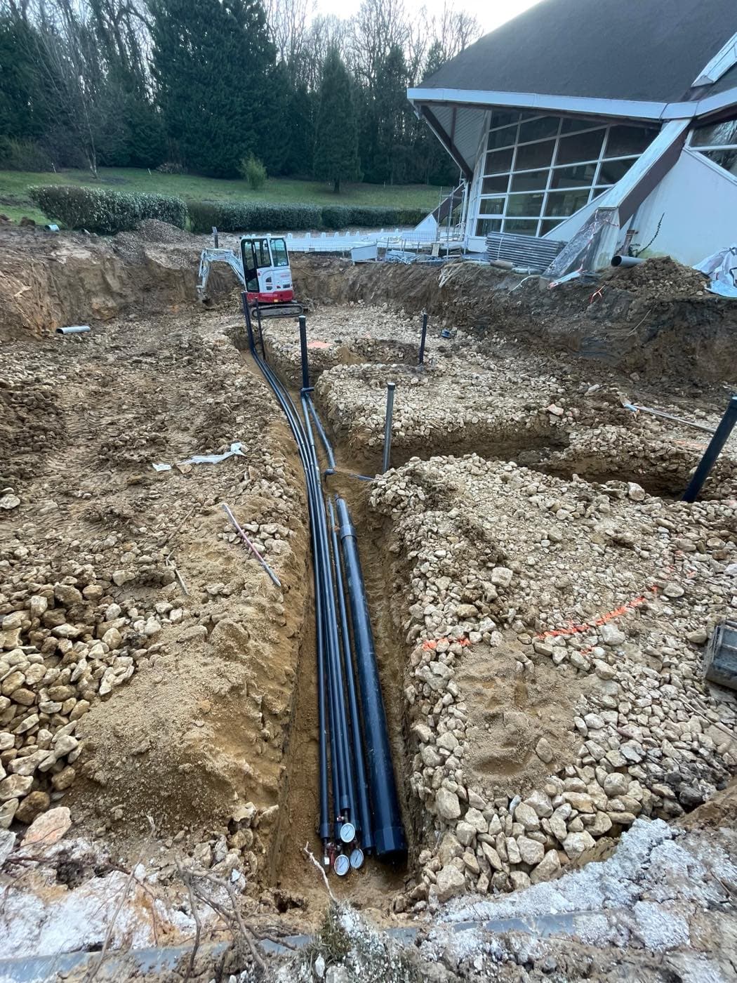 Terrassement et pose de canalisations pour un bassin public en construction